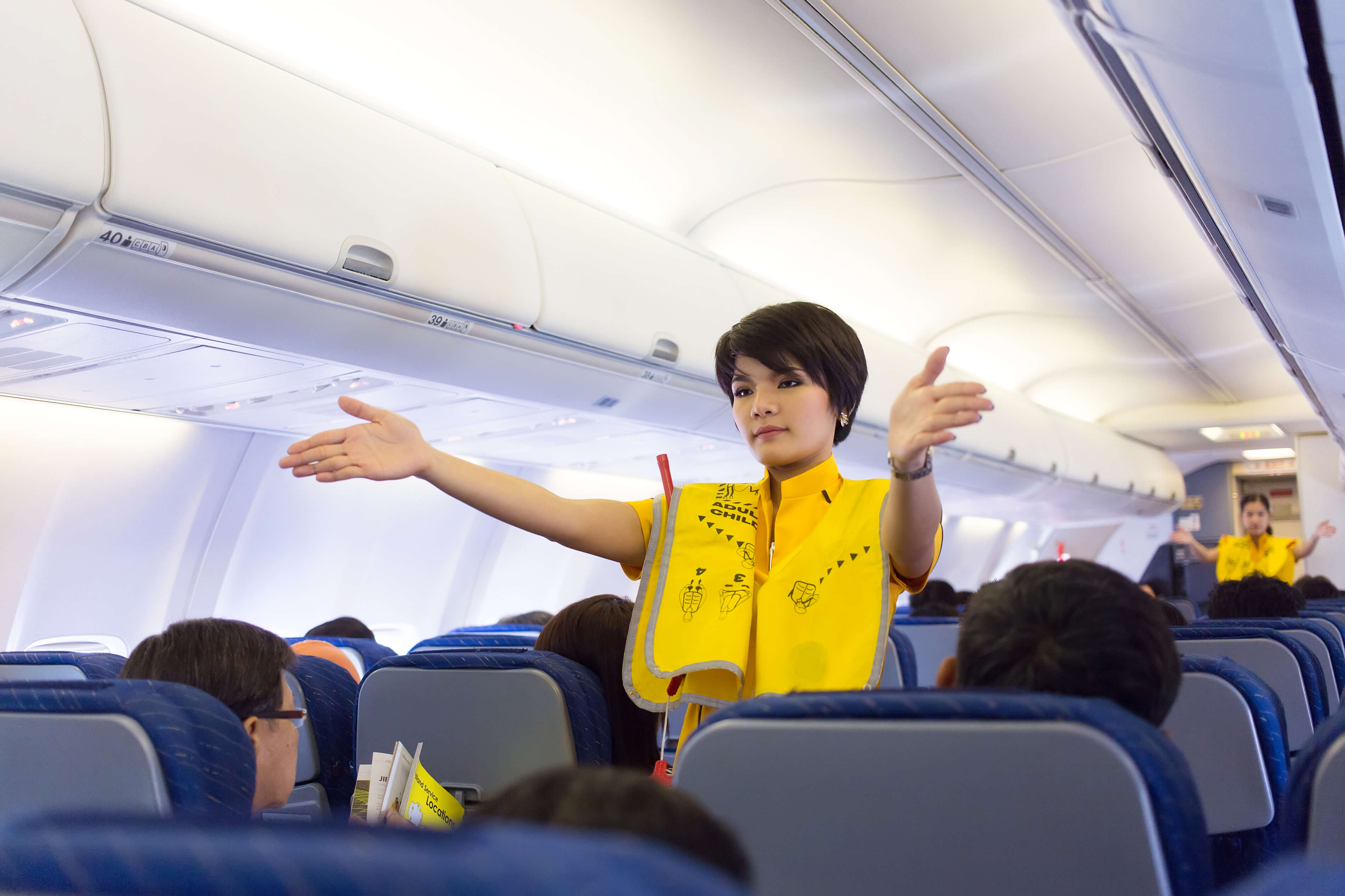 พนักงานต้อนรับบนเครื่องบินสาธิตอุปกรณ์ความปลอดภัย